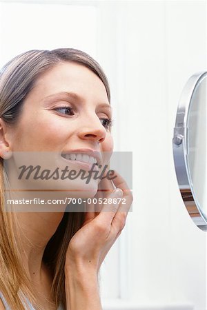 Femme regardant dans le miroir de salle de bains