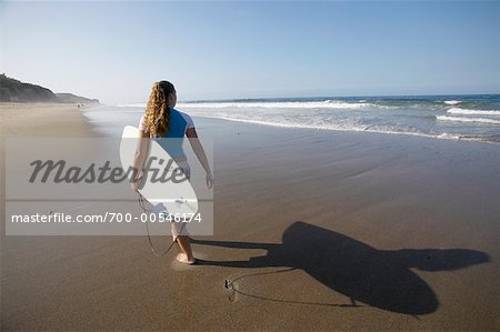 Frau zu Fuß am Strand mit Surfbrett