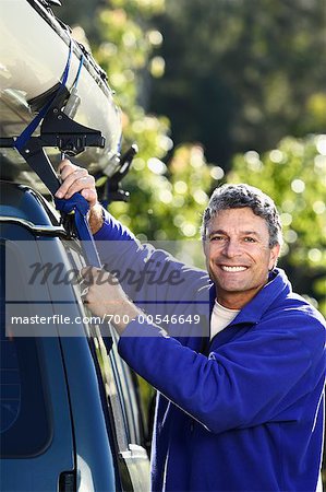 Man Fastening Kayak to Car Roof