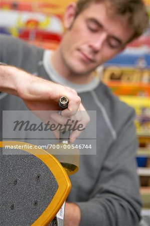 Man Adjusting Wheel on Skateboard