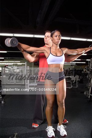 Femme, soulever des poids avec Personal Trainer