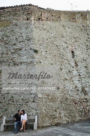 Couple on Park Bench by Wall, Castiglione della Pescaia, Tuscany, Italy