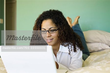 Femme au lit avec ordinateur portable