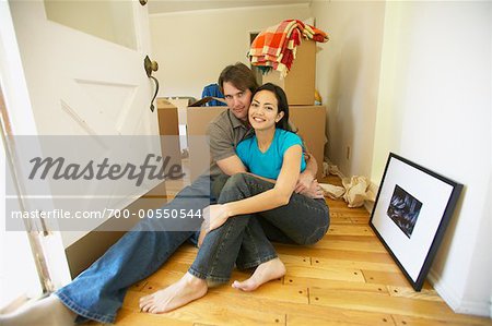 Couple Sitting On Hallway Floor On Moving Day