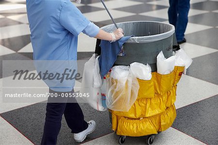 Personne qui pousse la poubelle avec les fournitures de nettoyage