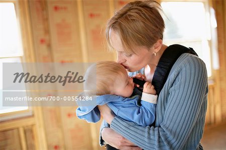 Mère embrassant bébé dans la maison inachevée