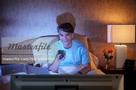 Homme regarder la télévision au lit
