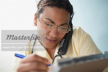 Doctor Writing on Clipboard, Talking on Telephone