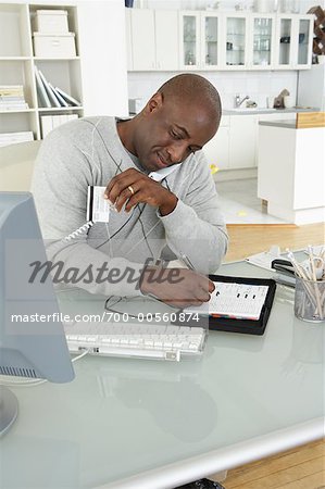 Man at Computer with Credit Card, Telephone and Day Timer