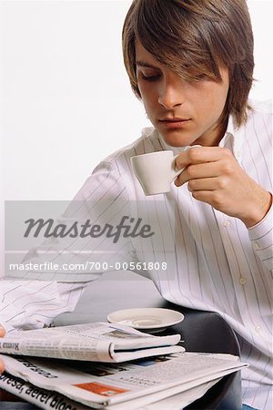 Jeune homme buvant café et journal de lecture