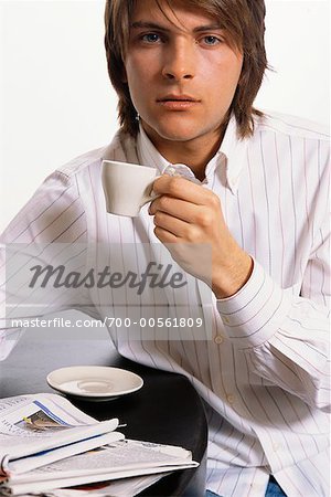 Portrait de jeune homme boire du café et en lisant le journal