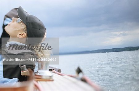 Woman on boat looking up at cloudy sky