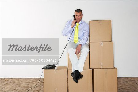 Homme d'affaires en utilisant le téléphone tout en étant assis sur les boîtes