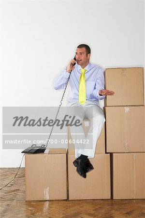 Geschäftsmann mit Telefon sitzen auf Boxen