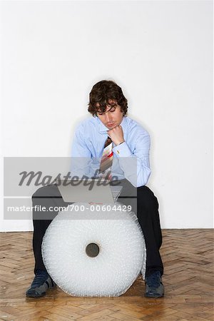 Businessman Sitting on Bubble Wrap Roll