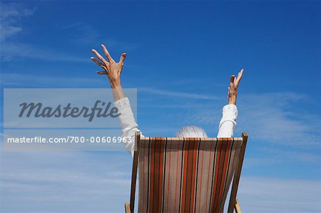 Femme en chaise de plage avec les bras en l'Air