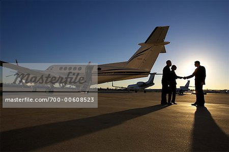 Gens d'affaires sur le Tarmac avec des avions en arrière-plan