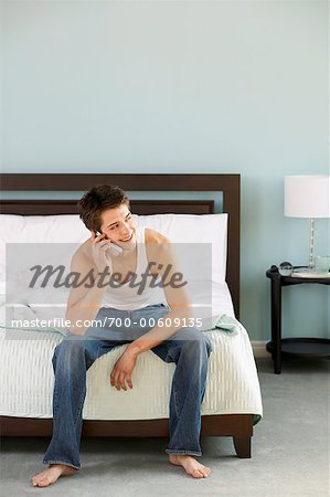 Boy Sitting on Bed with Cellular Phone