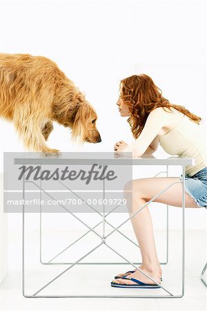 Dog Climbing Onto Table Where Woman Is Sitting