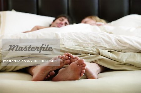Close-up of Couple's Feet In Bed