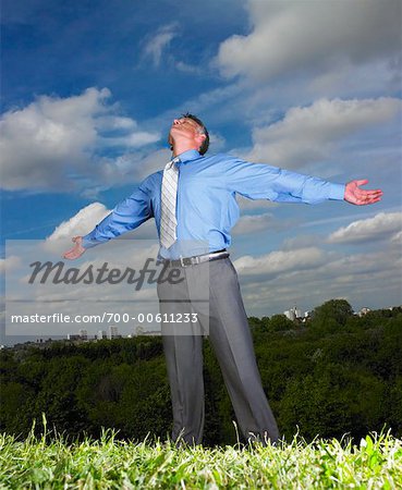 Businessman Standing in Field With Arms Open Wide