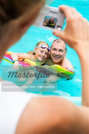 Woman Taking Picture of Father And Daughter in Swimming Pool