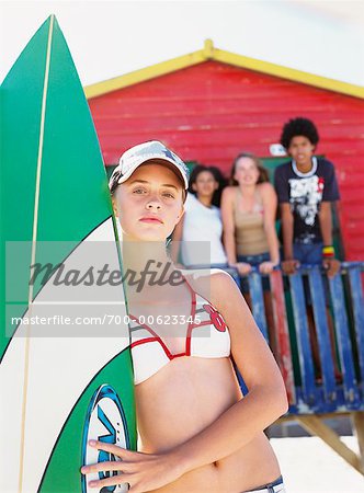 Jeune femme tenant la planche de surf sur la plage