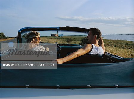 Femme parle à l'homme en cabriolet sur une route de campagne