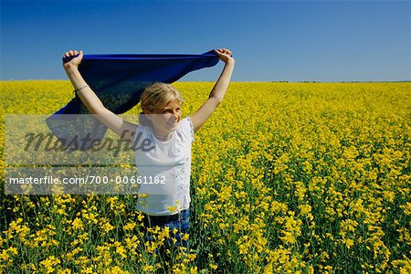 Fille dans le champ de Canola, tenant le chiffon jaune