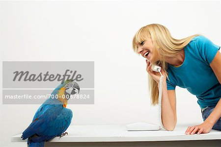 Frau Gespräch am Telefon neben blau und gelb Macaw