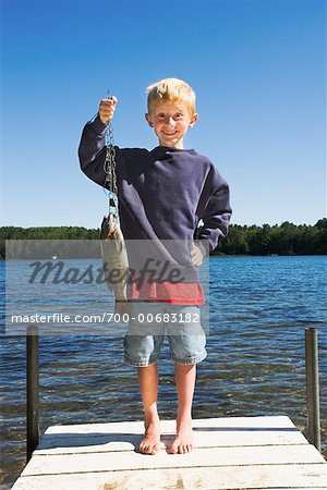 Garçon montrant des poissons qu'il a attrapé
