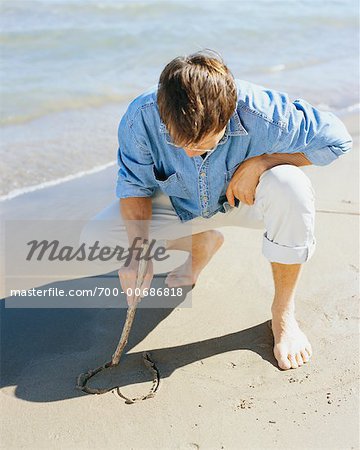 Homme dessin coeur dans le sable