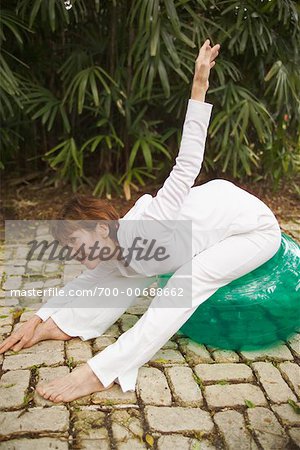 Woman Doing Stretches On Exercise Ball Outdoors