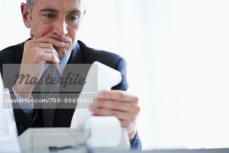 Man Looking at Adding Machine Print-Out