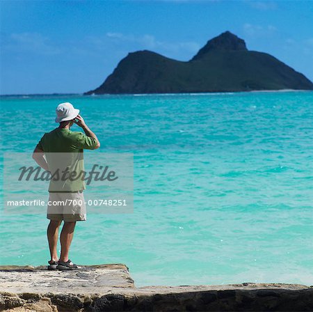 Man Standing On Rock by Ocean, Talking on Cellular Phone, Oahu, Hawaii