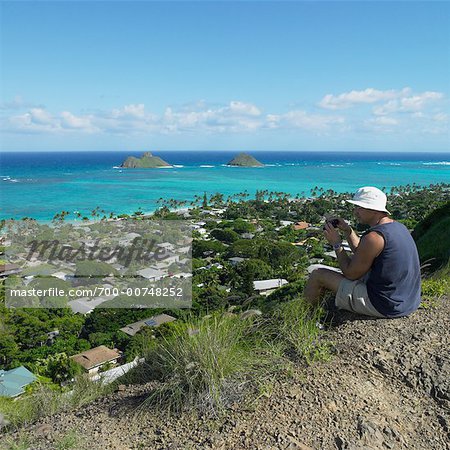 Man With Binoculars Sitting On Hill, Hawaii