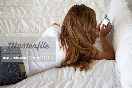 Femme allongée sur le lit, à l'aide de téléphone portable