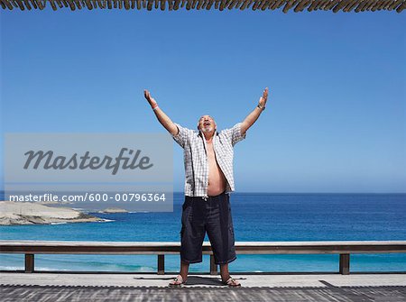Man Standing by the Beach, Arms Raised in the Air