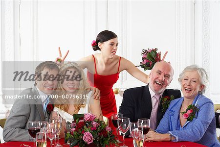 Bridesmaid Making Hand Gestures Behind Backs of Wedding Guests