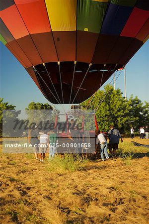 Rear view of people pulling hot air balloon