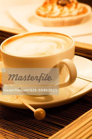 Close-up of a cup of coffee with sugar candy and a cookie