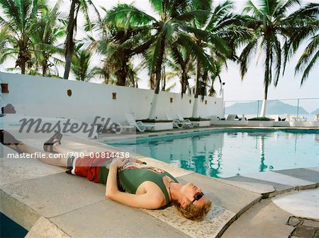 Homme couché près de piscine