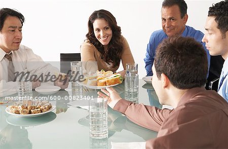 Geschäftsleute mit Snacks im Sitzungssaal