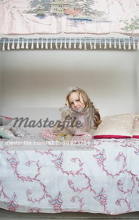 Girl Sitting on Bed, Holding Teddy Bear and Wearing Tiara