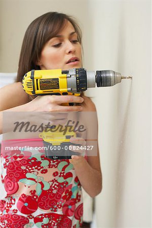 Woman Drilling Hole in Wall
