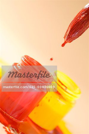 Close-up of a paintbrush over a bottle of red paint