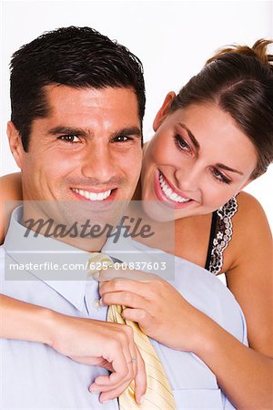 Close-up of a young woman adjusting a mid adult man's tie