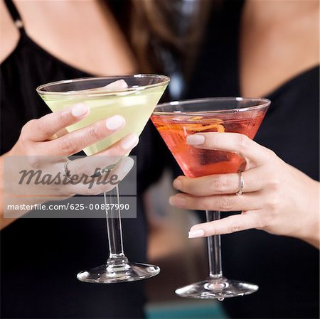 Mid section view of two young women toasting martinis