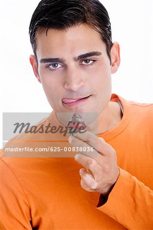 Portrait d'un homme adult milieu tenant un chocolat fraises trempées devant sa bouche