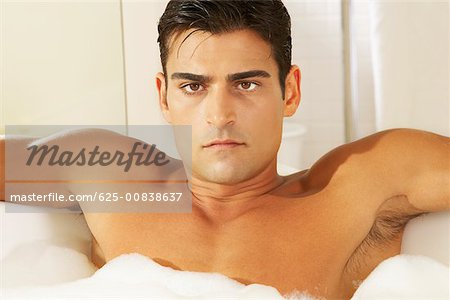 Portrait d'un jeune torse nu dans un bain moussant